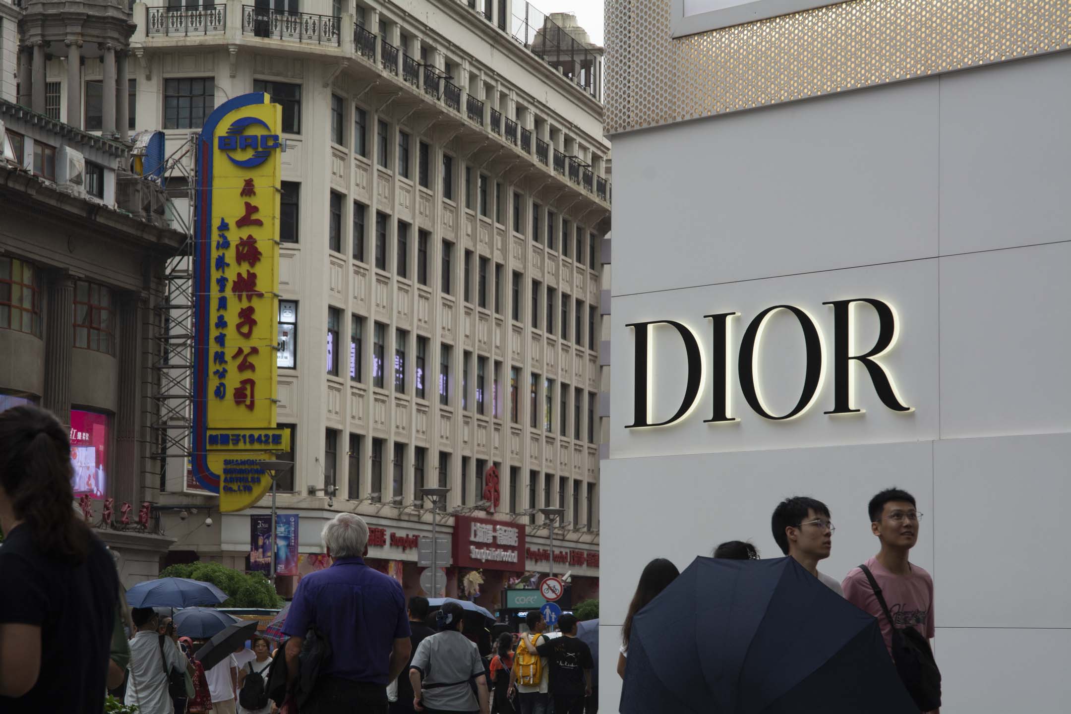 2024年6月22日,遊客走過中國上海南京東路中心購物區的 Dior 店。攝:Ying Tang/NurPhoto via Getty Images