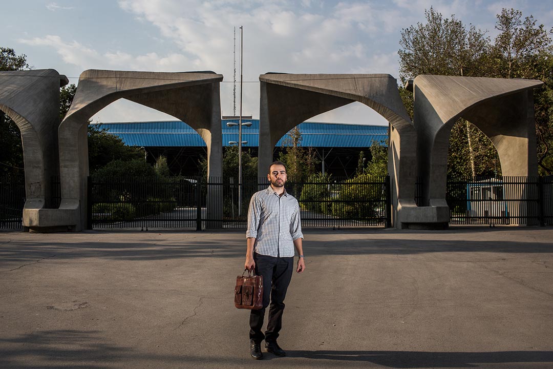Mohammad Ali Mir Bagheri,三十歲的德黑蘭大學哲學系博士生,站於大學入口處。德黑蘭大學是伊朗其中一間「常春藤盟校」。為了維持生計,他正在做多份兼職。但他無法找到與他學科有關的工作。攝:Arash Khamooshi/端傳媒